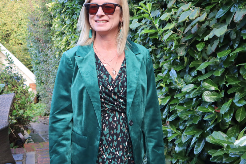 v neck wrap dress in green animal print worn with a green velour blazer, both from Afibel