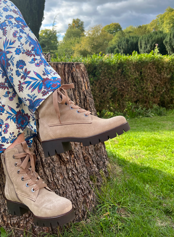 Michelle is sitting on a tree stump wearing the gabor best fit ankle boots in desert shade