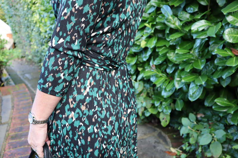 back view of a green animal print dress with a tie waist from afibel