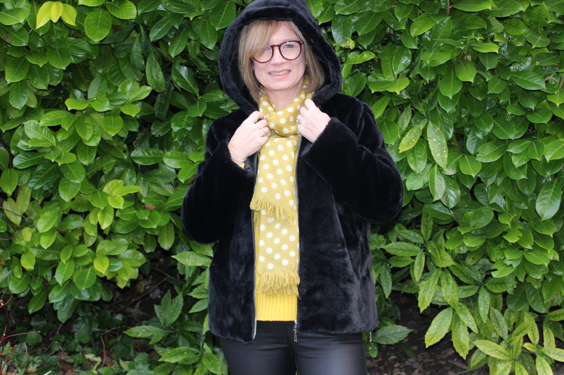 wearing black fur coat with bright yellow knit from Boden