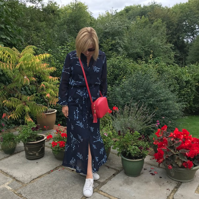 woman in garden with navy dress and red bag