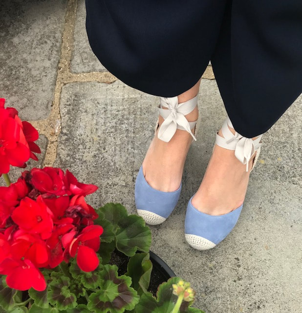 blue espadrilles on woman and next to red flowers
