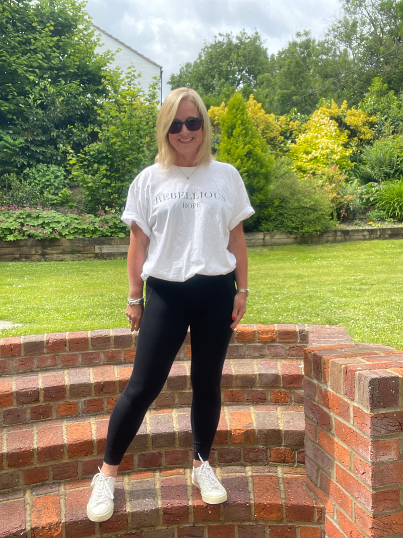 fifty and fab in the garden wearing rebellious hope white t-shirt with black leggings