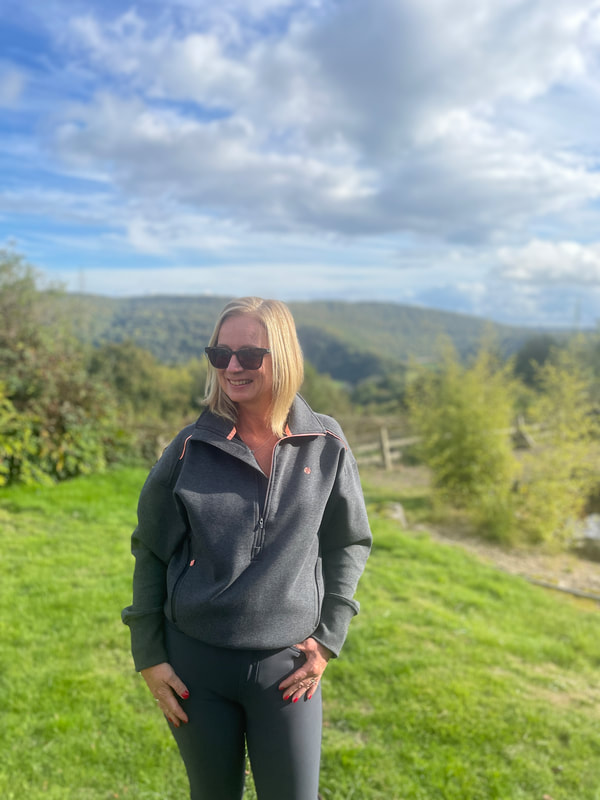 michelle is standing in front of the view of the ancient forests and she is wearing a grey outfit from ACAI outdoorwear