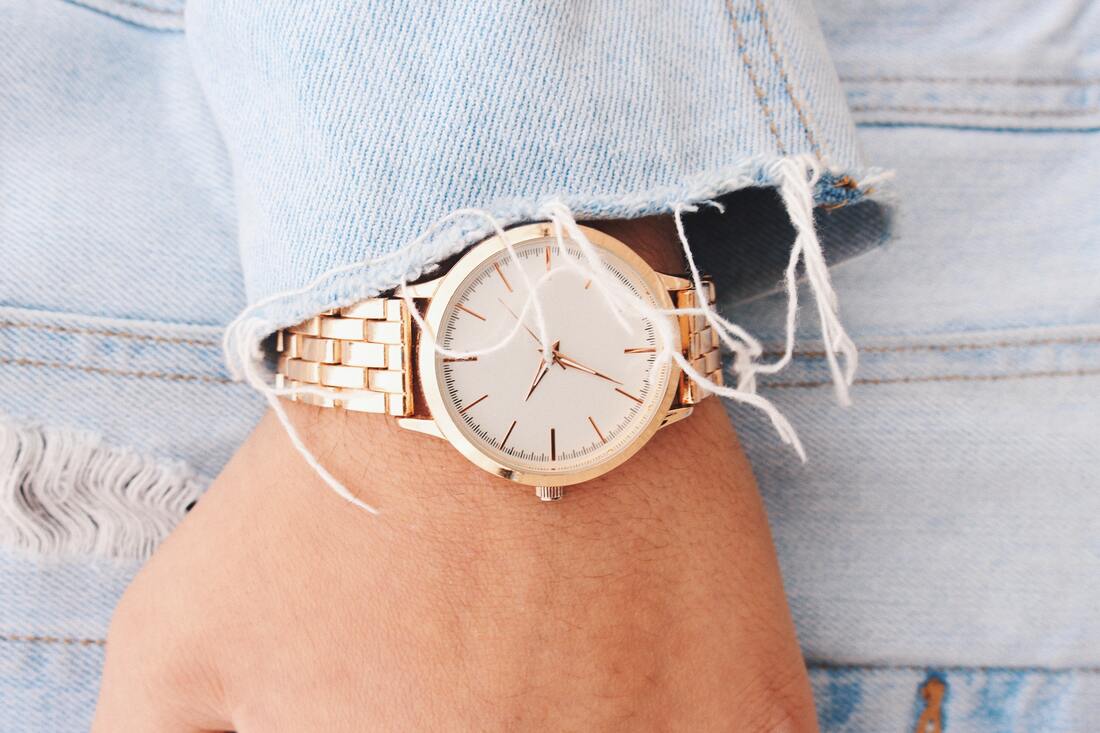 female hand wearing denim jacket and wearing a gold watch