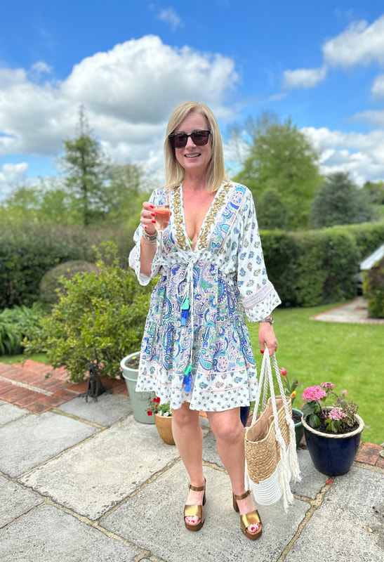 Michelle is in the garden and she is wearing a Miss June beach dress from Beach Cafe and holding a straw bag