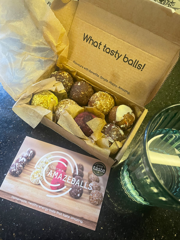 Claire's Amazeballs in a cardboard box with a glass of water - energy balls