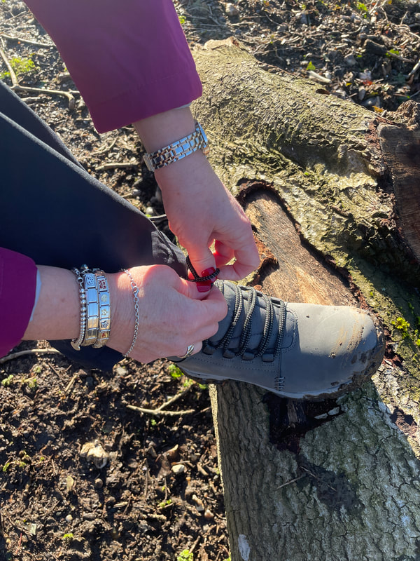 doing up a pair of walking boots for women on a log in the woods