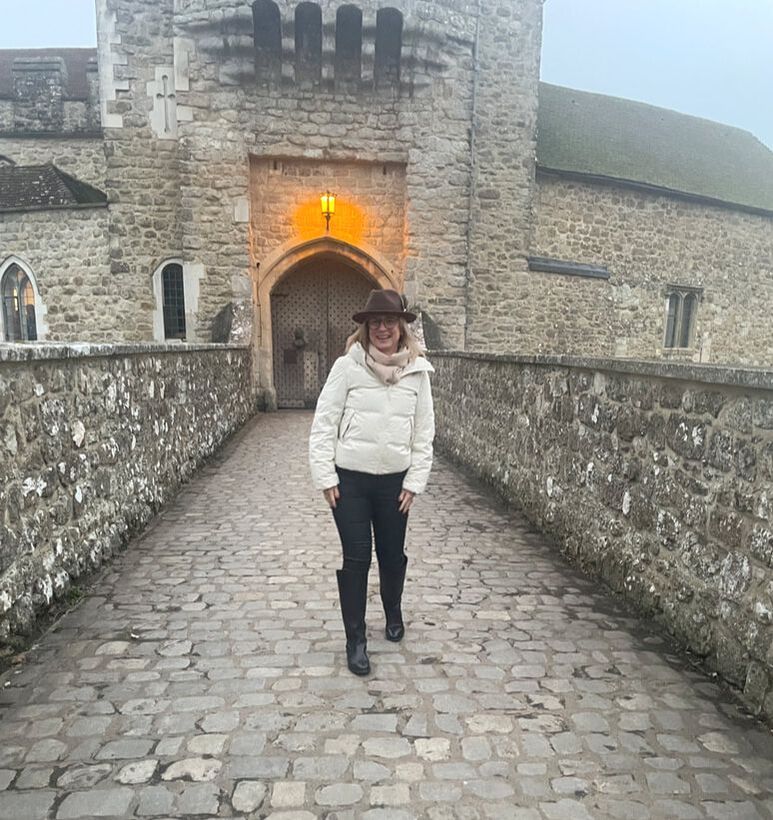 woman in cream jacket standing on drawbridge at Leeds Castle in Kent