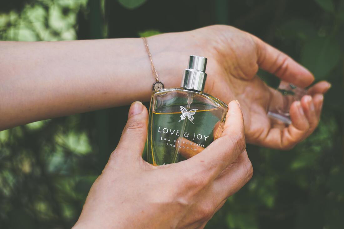 glass bottle of perfume Love & Joy and female hands | fragrance samples UK
