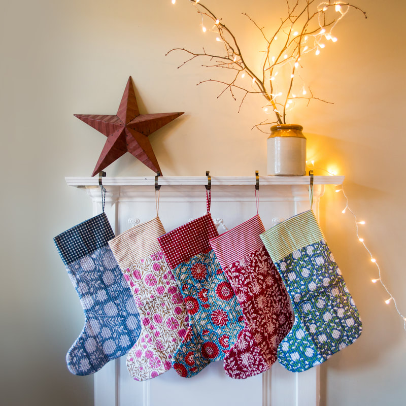 christmas stockings from happy cabbage displayed on a white fireplace with red star and fairy lights