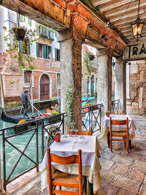 Romantic Italy, tables for two, in Venice with gondola going past