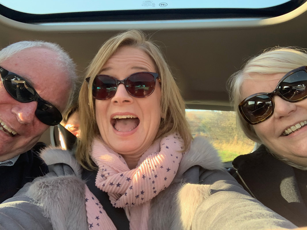 one man and two women laughing and taking a car selfie