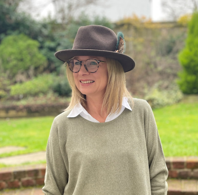 white shirt layered under a green jumper and styled with fedora hat