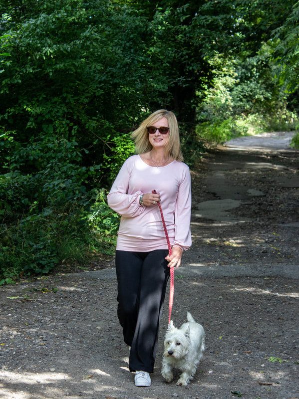 woman walking westie dog in woods