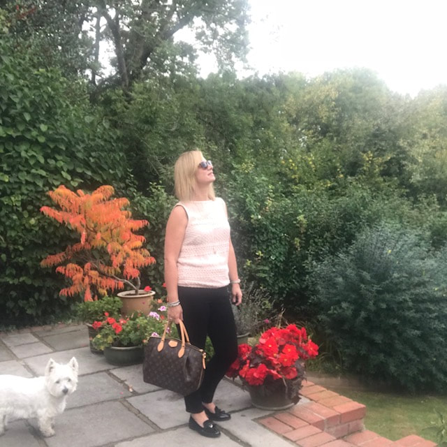 woman in black jeans in garden with westie dog