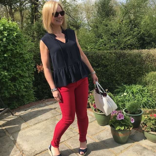 woman in red jeans and white handbag in garden
