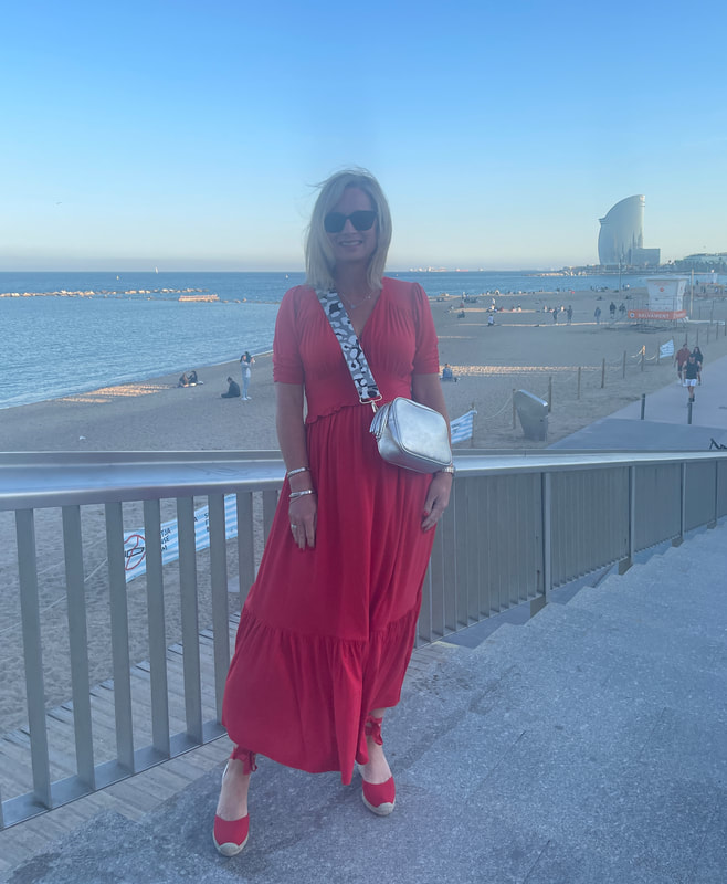 woman in red dress standing by Barcelona beach