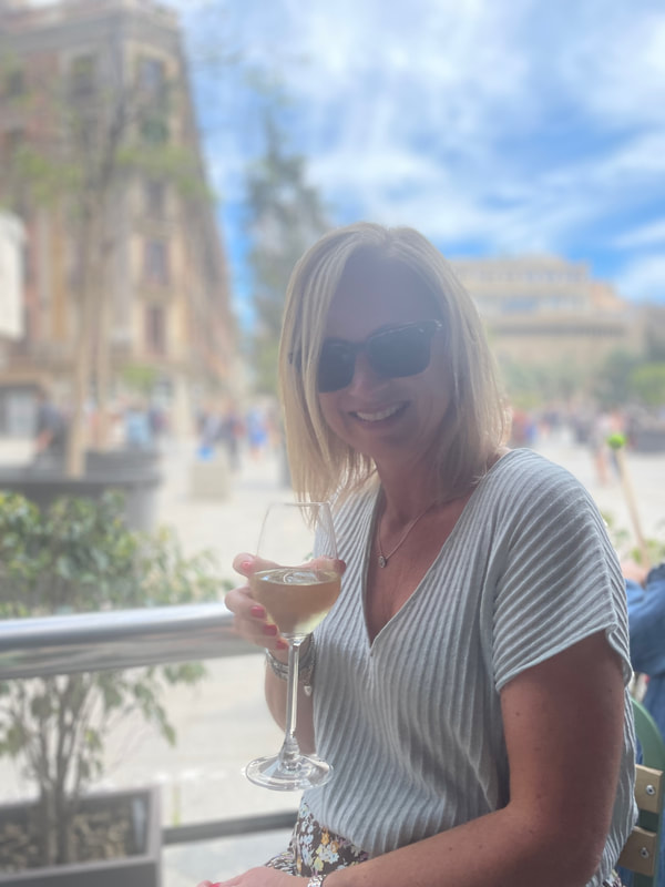 woman in green top enjoying a glass of white white at a cafe by Barcelona cathedral