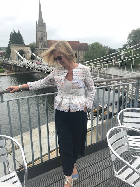 woman with hair blowing in wind standing by marlow bridge at marlow rowing club