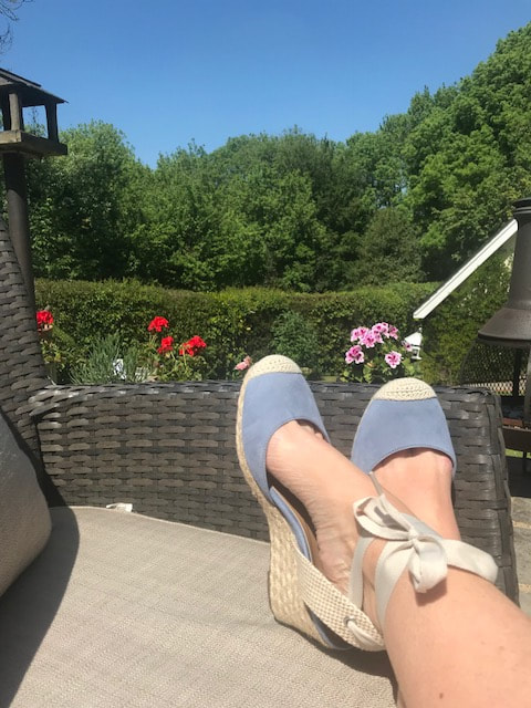 blue espadrille shoes feet up on chair in garden blue sky