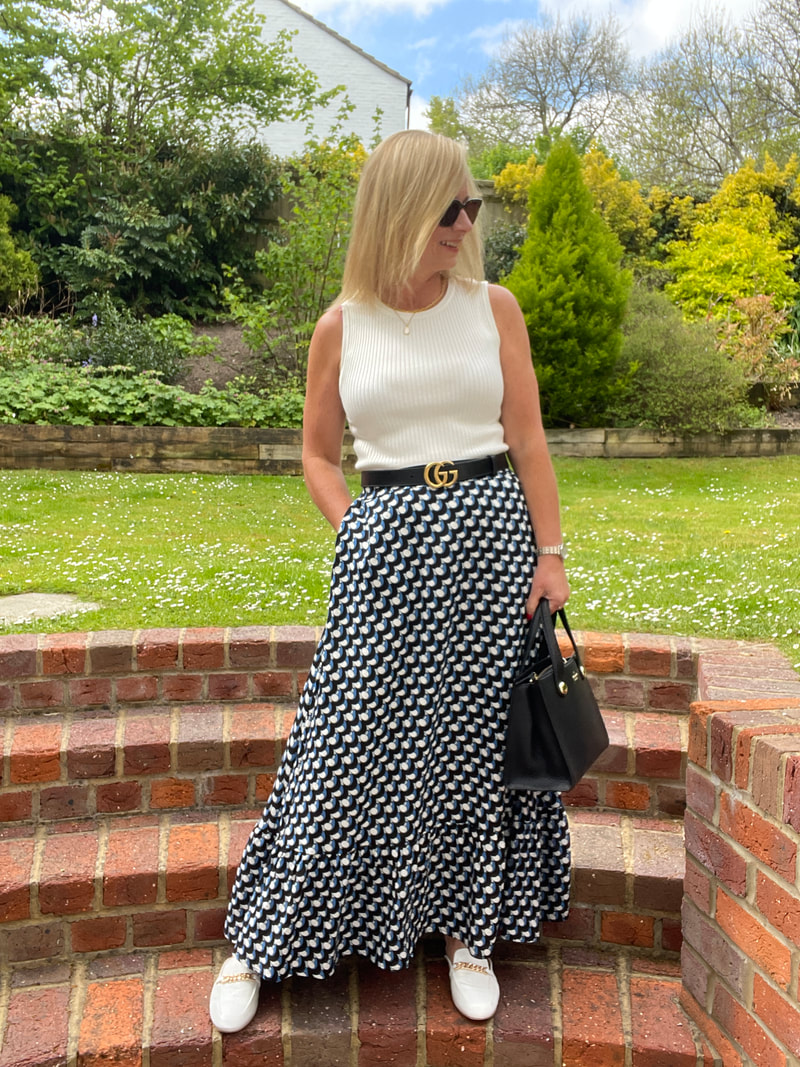 woman standing in garden wearing a blue and black geo print skirt from saint and sofia
