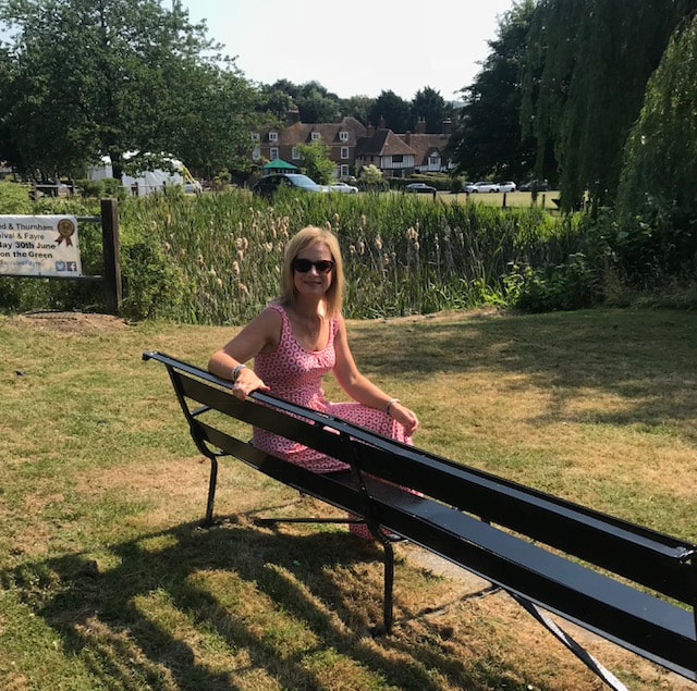 woman on bench bearsted village green and cricket