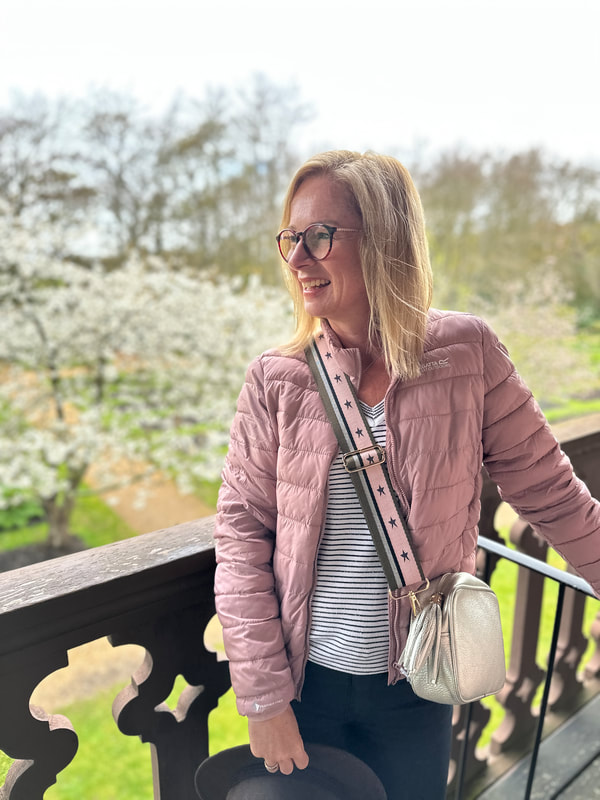 michelle wearing a dusky rose jacket and standing on the balcony at the swiss cottage at osborne house on the isle of wight
