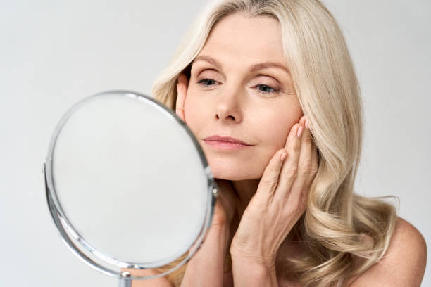 a beautiful woman looking in a mirror | exercise for sagging jowls