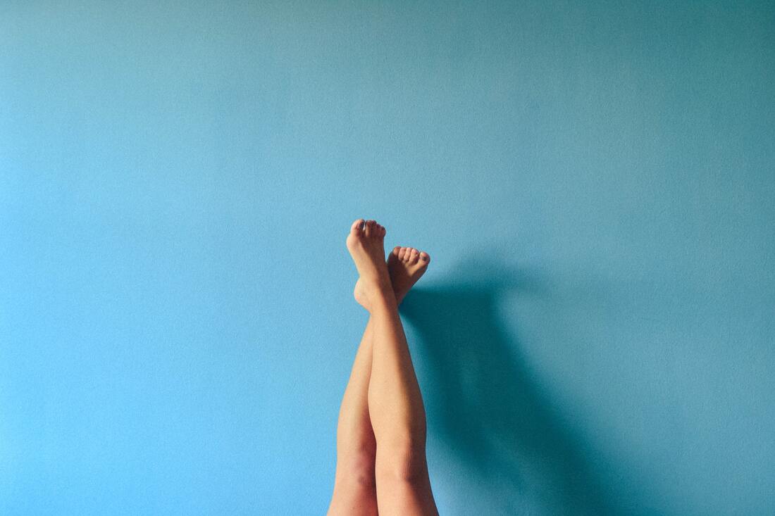 feet crossed over against a blue wall