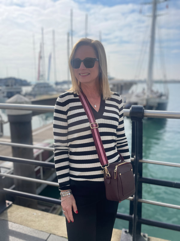 Michelle is wearing a black and white stripe top from Baukjen and is standing by the railings at Portsmouth marina