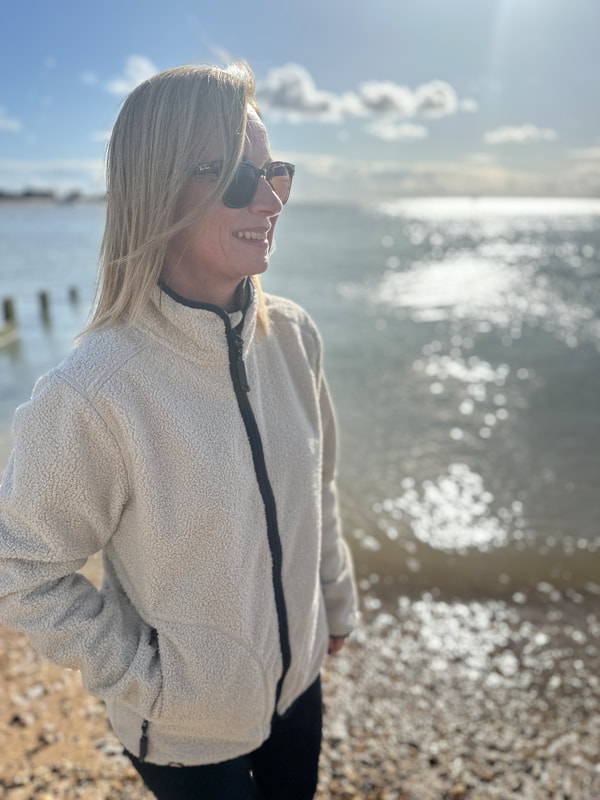 Michelle is standing on the beach at Brightlingsea in Essex wearing an ACAI fleece jacket