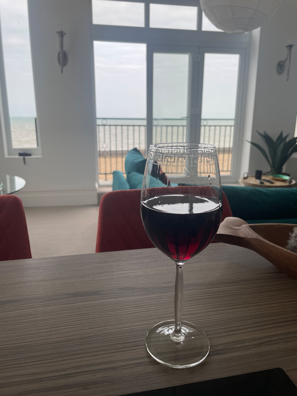 glass of red wine on a table in an apartment overlooking the beach
