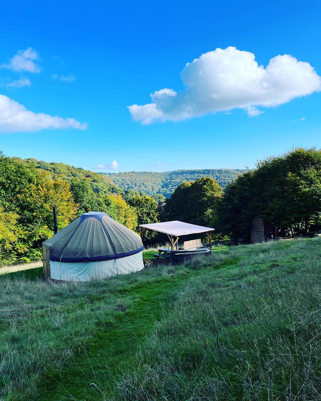 yurt at hill farm glamping site in tintern, in a green field with blue skies and view of the ancient forests