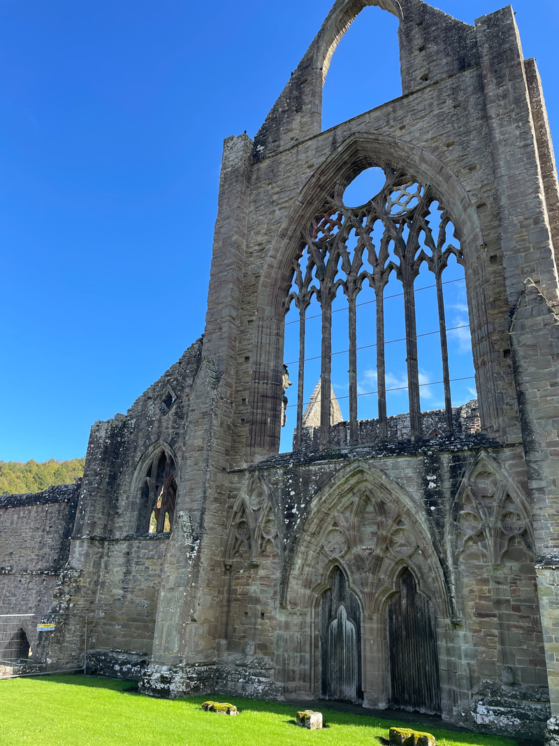 a view of tintern abbey in the sun, with a bright blue sky behind