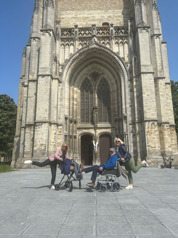 man in a wheelchair with his three daughters outside the roman catholic cathedral in ypres belgium